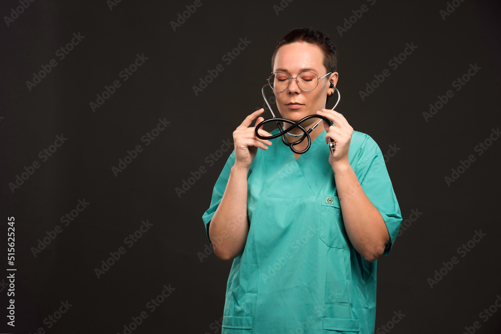 Female doctor in green uniform holding a stethoscope and wearing it Female doctor in green uniform holding a stethoscope and wearing it