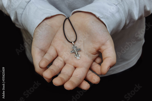 Children's palms, teenager's hands hold an Orthodox cross close-up, the concept of religion, faith and hope, prayer, the sacrament of communion, requests from the needy, community help, God Jesus photo