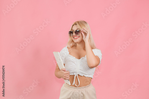 a beautiful girl in glasses with a book in her hands poses on a pink background © Павло Товтин