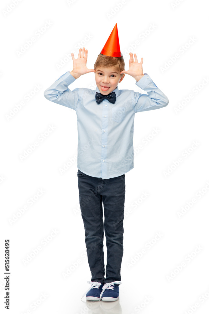 birthday, childhood and people concept - portrait of smiling little boy in party hat and bowtie making faces over white background birthday, childhood and people concept - portrait of smiling little boy in party hat and bowtie making faces over white background