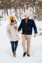 people, love and leisure concept - happy smiling couple walking in winter forest