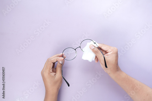 cleaning eyeglass with tissue close up 