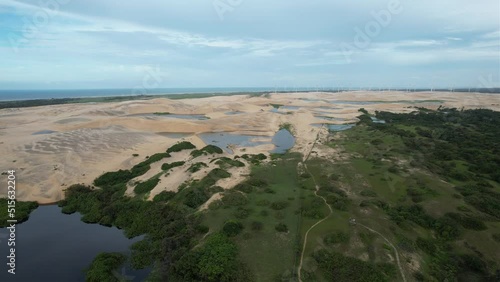 Side drone tracking of a lake with dunes and beautiful landscape, lush nature of northeast brazil photo
