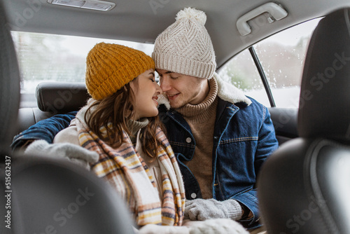 people, love and leisure concept - happy smiling couple hugging and rubbing noses on car back seat in winter