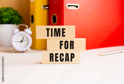 Wooden cubes stacked on top of each other make up the TIME FOR RECAP inscription. Design on the desktop.