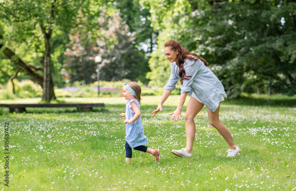 Fototapeta premium family, motherhood and people concept - happy mother with little daughter playing at summer park or garden