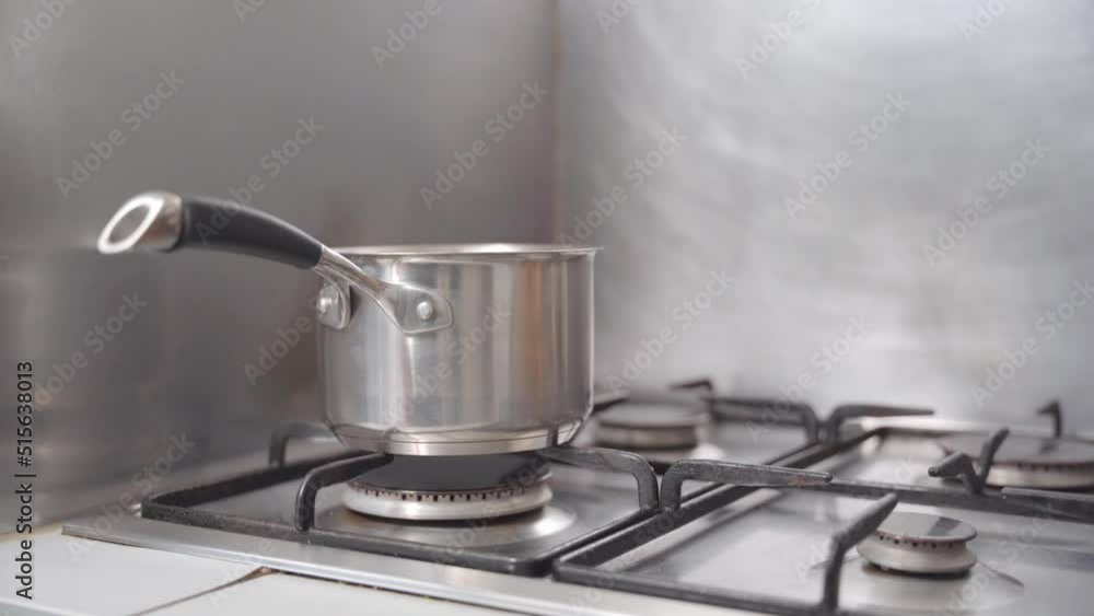 static shot of a pot being put on a stove. Chocolate is then being put inside the pot to be cooked in a bain marie.
