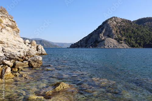 Picturesque view to rock cliff in Mediterranean sea. Summer coast with turquoise transparent water and green mountains © Oleg