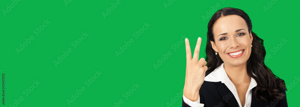 Businesswoman in black confident suit showing two fingers, isolated on vivid green background. Happy smiling brunette woman at studio. Business success concept. Businesswoman in black confident suit showing two fingers, isolated on vivid green background. Happy smiling brunette woman at studio. Business success concept.