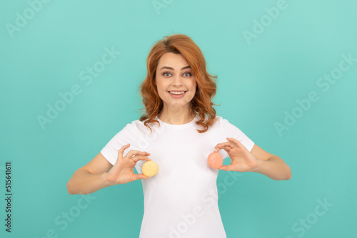 cheerful woman hold sweet macaron french cookie on blue background