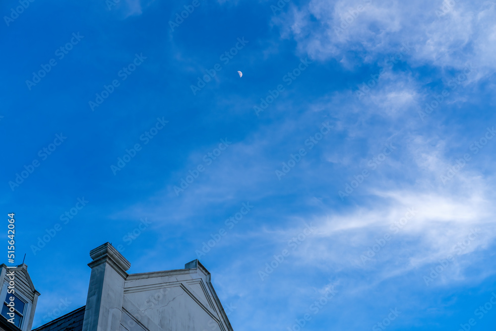 Half moon in the distant sky with top of historic building in the corner and mostly negative space Half moon in the distant sky with top of historic building in the corner and mostly negative space