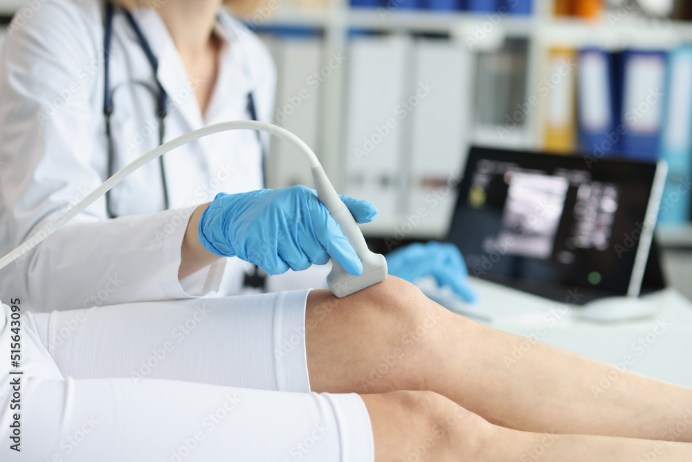Orthopedic doctor makes ultrasound examination of tpatient knee in clinic