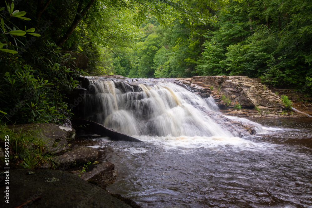 Fototapeta premium Waterfall in forest cascading down rocks slow shutter speed horizontal