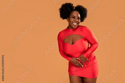 Happy afro Woman posing in fashionable red mini dress, looking at the camera and smiling. Glamour makeup. Date time photo