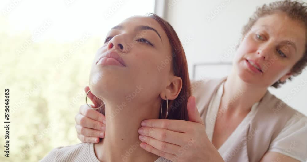 A mature chiropractor talking and explaining while examining patients neck and throat. Young woman receiving a massage or assessment for a spinal adjustment for better posture and alignment at a spa