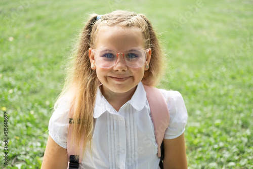 close up portrait of blonde schoolgirl in glasses white shirt with pink backpack back to school