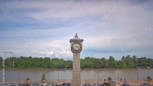 Chachoengsao , Thailand - 7 July 2022: Take in the view on the Bang Pakong River Promenade, where the clock tower contrasts with the blue sky and soft clouds.clock tower riverside street 