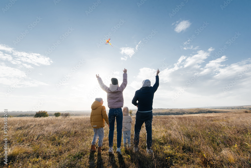 A happy family with children flies a kite and spends time together outdoors in a nature reserve. Happy childhood and family holidays. Freedom and space. A happy family with children flies a kite and spends time together outdoors in a nature reserve. Happy childhood and family holidays. Freedom and space.