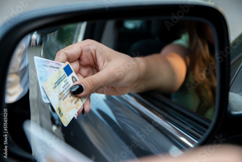 Teenager driver commited a minor offence and handing over her licence to a police officer reaching towards the open window.Police officer controlling traffic on the road photo