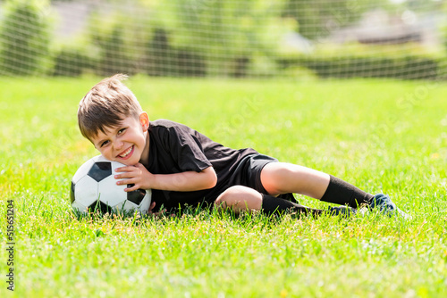 Cute boy playing football enjoying sport game outside
