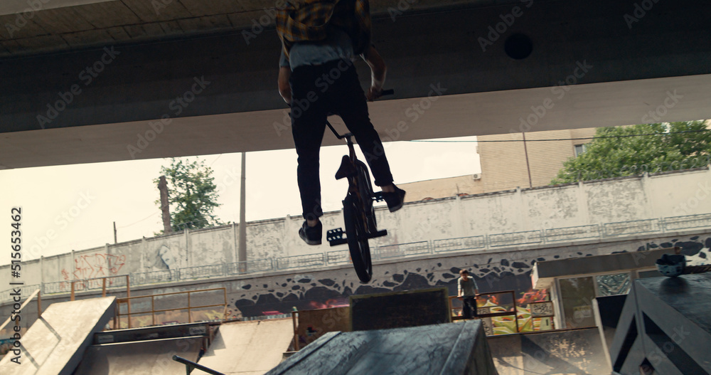 Active bmx rider training skills at skatepark. Biker racing up in ramp. Active bmx rider training skills at skatepark. Biker racing up in ramp.