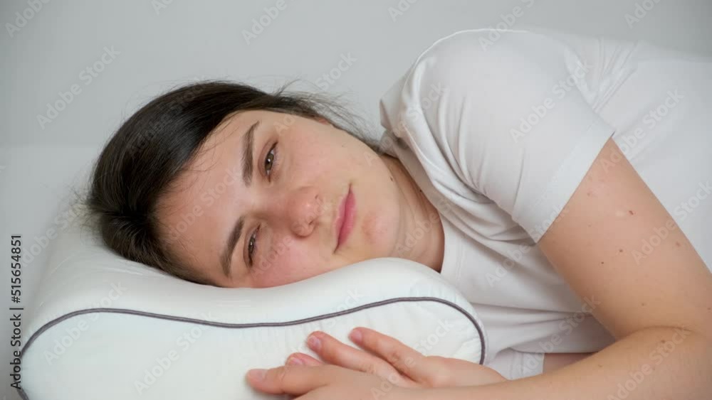 A woman sleeps on an orthopedic pillow made of memory foam, opens her eyes and smiles A woman sleeps on an orthopedic pillow made of memory foam, opens her eyes and smiles