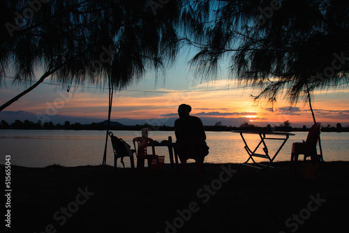 Silhouette of a man enjoying the sunset view by the riverside in Kampot, Cambodia