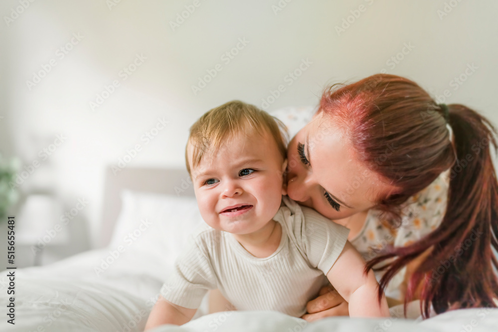Mother and baby on white bed at home Mother and baby on white bed at home