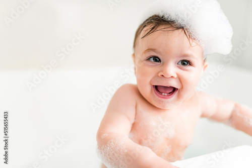 Baby boy bathes in a bath with foam and soap bubbles