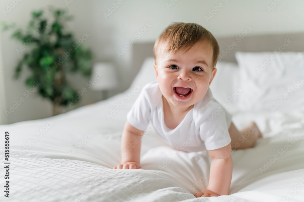 Adorable baby boy in white sunny bedroom in the morning at home Adorable baby boy in white sunny bedroom in the morning at home