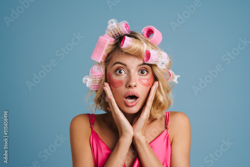 Young woman with curlers and eye patches expressing surprise