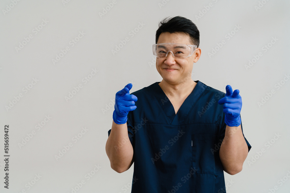 Asian health worker wearing protective gloves pointing fingers at camera Asian health worker wearing protective gloves pointing fingers at camera