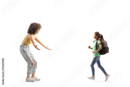 Full length profile shot of a schoolgirl with a backpack running towards a young woman