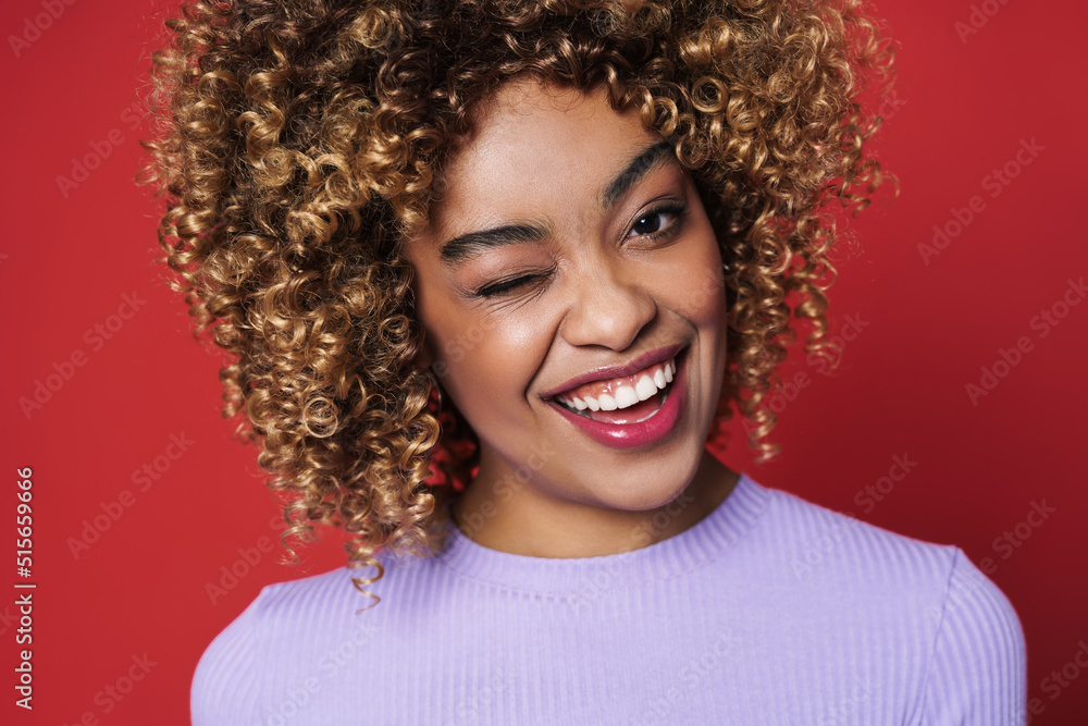 Young black woman with afro curls smiling and posing at camera Young black woman with afro curls smiling and posing at camera