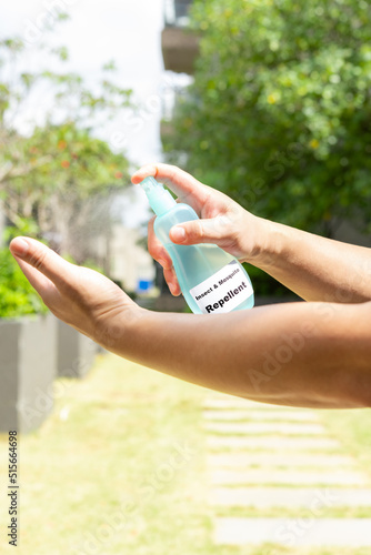 man spraying insect and mosquito repellent to his hand in the outdoor at vertical composition photo