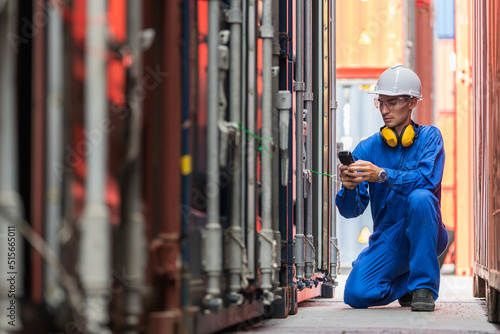 Dock worker man in safety vest holding barcode scanner and inspector the quality of container at shipping yard. Import and export product. Manufacturing transportation and global business concept