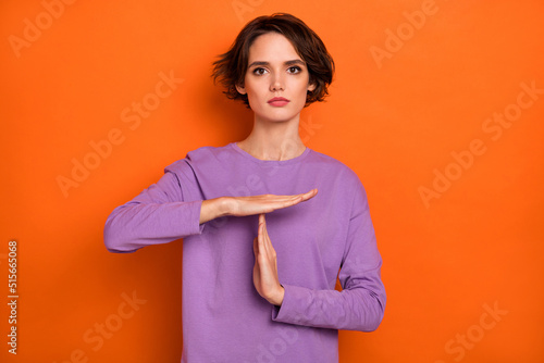 Photo of calm focused lady hands demonstrate timeout symbol isolated on orange color background photo