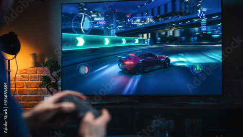 Close Up on Man\'s Hands at Home, Sitting on a Couch in Stylish Loft Apartment and Playing Arcade Car Video Games on Console. Male Using Controller to Play Street Racing Drift Simulator.