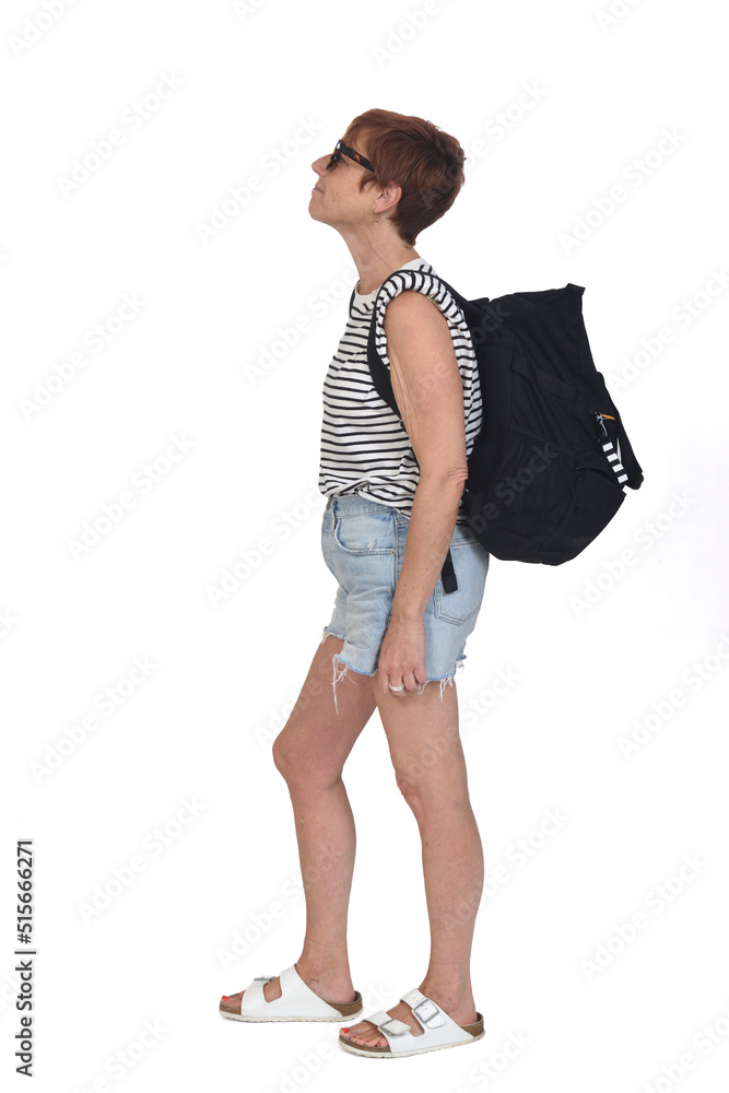 side view of a middle aged woman on a summer day with backpack lookig up with sunglasses on white background side view of a middle aged woman on a summer day with backpack lookig up with sunglasses on white background