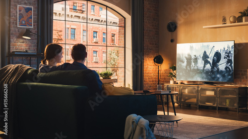 Bild auf Leinwand Authentic Couple Spending Time at Home, Sitting on a Couch and Watching Latest Blockbuster on Flat Screen Television Set
