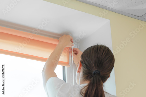 Female hands installing roller blinds on the window. Installation of roller blinds