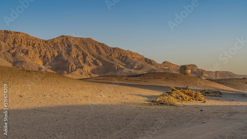 Balloons rise over the desert from the gorge. Shadows on the sand hills. A picturesque mountain range against a clear blue sky. Egypt. Luxor