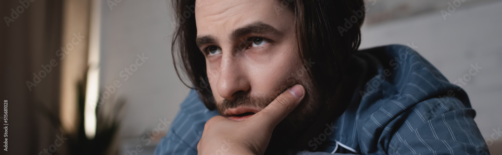 Tired man in pajamas looking away at home at night, banner Tired man in pajamas looking away at home at night, banner