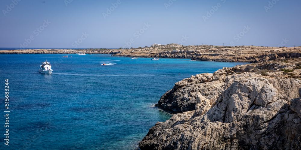 View of the sea and cliffs of Blue Lagoon, Cape Greco, Cyprus. Small boats anchored at the bay. 
