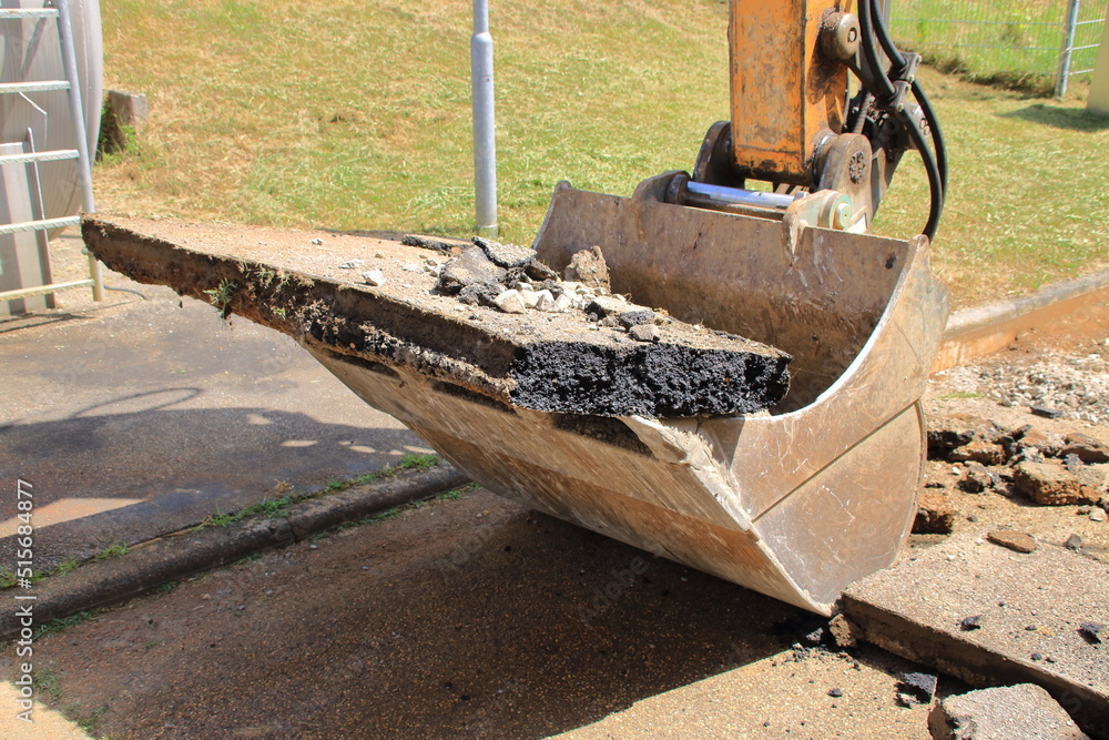 Schaufel von einem Bagger ist mit Asphaltbrocken gefüllt Schaufel von einem Bagger ist mit Asphaltbrocken gefüllt