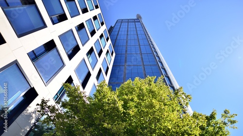 Bottom view of modern skyscraper in business district against blue sky. Looking up at business buildings in downtown. Rising sun on the horizon.