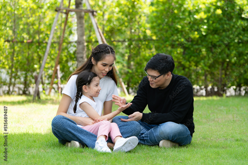 Asian family with both father, mother and daughter having fun in the garden of the house happily Asian family with both father, mother and daughter having fun in the garden of the house happily