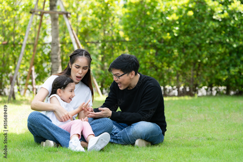 Asian family with both father, mother and daughter having fun in the garden of the house happily Asian family with both father, mother and daughter having fun in the garden of the house happily