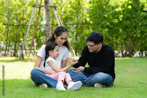 Asian family with both father, mother and daughter having fun in the garden of the house happily