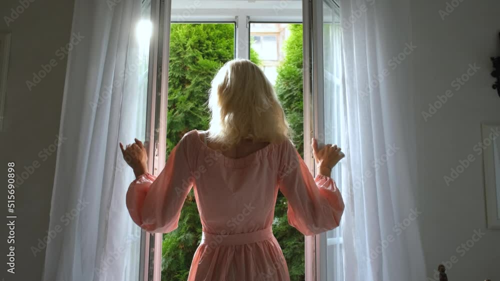 elegant woman opens window to sunny garden elegant woman opens window to sunny garden